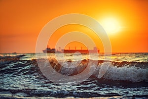 Sun setting at the sea with sailing cargo ship, scenic view