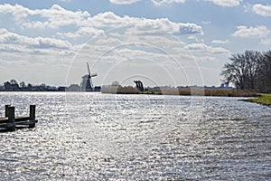 The sun shimmers in the choppy water of the lake De Rottemeren near windmill De Korenmolen on a sunny and windy day photo
