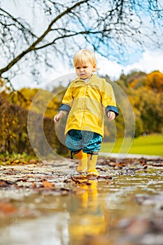 Sun always shines after the rain. Small bond infant boy wearing yellow rubber boots and yellow waterproof raincoat