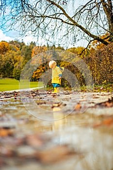 Sun always shines after the rain. Small bond infant boy wearing yellow rubber boots and yellow waterproof raincoat