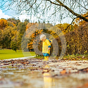 Sun always shines after the rain. Small bond infant boy wearing yellow rubber boots and yellow waterproof raincoat