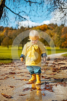 Sun always shines after the rain. Small bond infant boy wearing yellow rubber boots and yellow waterproof raincoat