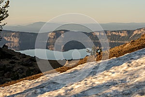 Sun Shines On Snow Bank With Crater Lake In The Distance