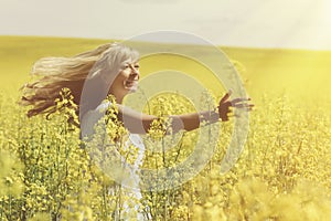Sun shines through woman`s blonde hair while she whirls on field.
