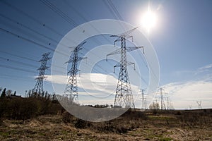 The sun shining behind electric power transmission lines