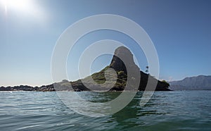 Sun shining on Mokolii island [also known as Chinamans Hat] as seen from the water on the North Shore of Oahu Hawaii United States