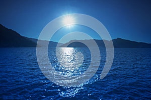 sun shining over blue water of fresh water lake and mountain background use for natural scen backdrop