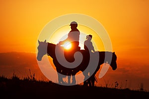 The sun is shining through silhouette of a woman riding a horse