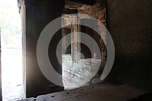 Sun shining through a window at stone pillar with ancient murals in famous histroical angkor wat ruins, cambodia