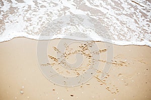 Sun sign on beach. Summer text, sun symbol on sandy beach with footprints and sea waves foam. Hello summer concept. Vacation,