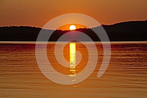 Sun sisappearing behind the mountains alon  Montargil lake, Portugal