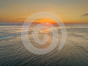 Sun sits low over ocean off coast