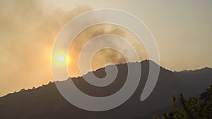 Sun in the sky through the smog from a forest fire in the mountains