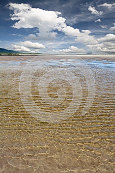 Sun sparkling in water over sandy beach