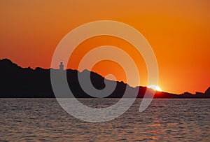 The sun at sunset behind the lighthouse and cape Higer, Euskadi
