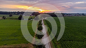 Sun Sunshine In Sunset Bright Sky. Beautiful Evening Sky Above Rural Landscape With Country Road. Young Green Wheat