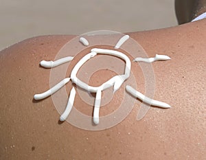 Sun symbol written in sunlotion on womans shoulder
