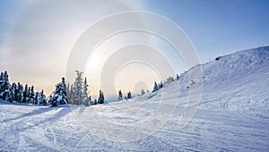 Sun trying to break through the clouds in the winter landscape of Sun Peaks ski hill