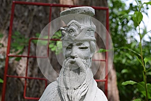 Sun Tzu statue in front of red garden arbor