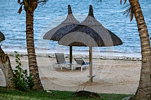 Sun umbrella and beach beds on tropical coastline, in Mauritius