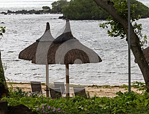 Sun umbrella and beach beds on tropical coastline, in Mauritius