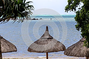 Sun umbrella and beach beds on tropical coastline, in Mauritius