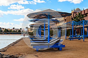 Sun umbrellas and chaise lounges on tropical beach. Concept of rest, relaxation, holidays, resort