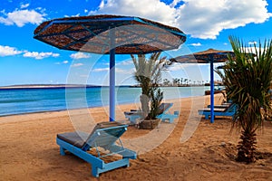 Sun umbrellas and chaise lounges on tropical beach. Concept of rest, relaxation, holidays, resort