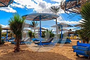 Sun umbrellas and chaise lounges on tropical beach. Concept of rest, relaxation, holidays, resort