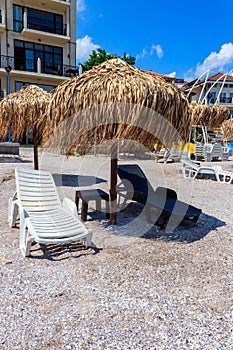 Sun umbrellas and chaise lounges on tropical beach. Concept of rest, relaxation, holidays, resort