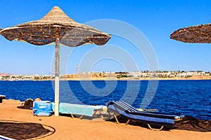 Sun umbrellas and chaise lounges on tropical beach. Concept of rest, relaxation, holidays, resort