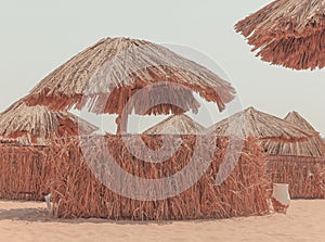 Sun umbrellas on the Egyptian hotel beach. Thatched sunshades and sunbeds for tourists, on a yellow sand beach.