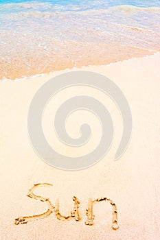 Sun word drawn on caribbean white sand with caribbean sea background