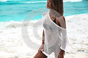 Sunbathed woman model in transparent white blouse posing on summer beach