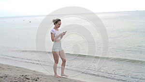 Sunbather girl wearing bikini using a smart phone on summer holidays on the beach