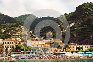 Sunbathers on the beach of Amalfi town, preceding the hills and historic town, the Amalfi coast, Italy.