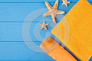 Sunbathing concept.Top above overhead view close-up photo of sunscreen yellow towel and starfish isolated on blue wooden