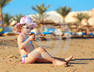 Sunbathing kid girl in hat sitting