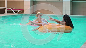 Sunbathing multiracial Caucasian Hispanic women girl model laughing swimming on inflatable ring in pool active leisure