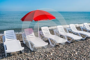 Sunbathing plastic beds and red umbrella on the beach