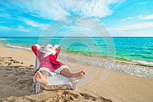 Sunbathing Santa Claus relaxing in bedstone on beach - Christmas