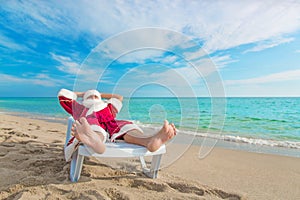 Sunbathing Santa Claus relaxing in bedstone on beach - Christmas