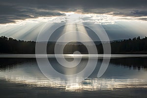 Sunbeam breaks through clouds, casting radiant glow over tranquil lake