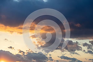 Sunbeams through dark clouds on blue sky background