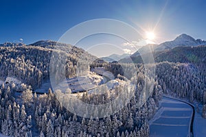 Sunbeams on a snowy winter`s day in the forest and mountain landscape with roads