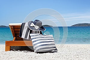 Sunbed with bag, blue hat and towel in the beach