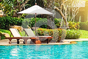 Sunbed with beach umbrella on side of swimming pool. Relaxing fa