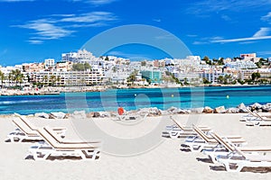 Sunbeds and beautiful city view on a beautiful beach in Ibiza, Spain.