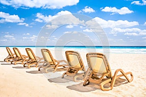 Sunbeds chaise longue at tropical empty beach and turquoise sea