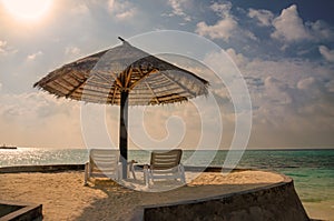 Sunbeds and palm tree umbrellas on a background of a beautiful sunset over the Indian Ocean, Maldives